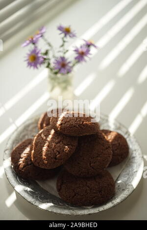 Sweet cookies in a silver vintage plate on a windowsill with a bouquet of flowers. Stock Photo