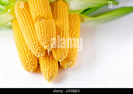 Fresh young corn with green leaves lies on a white background Stock Photo