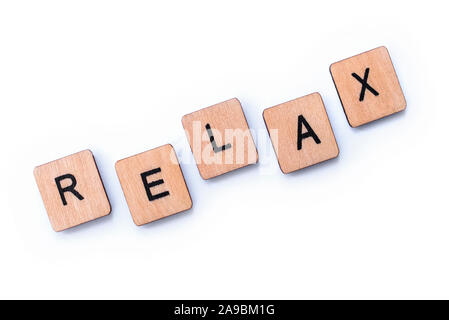 The word RELAX, spelt with wooden letter tiles over a white background. Stock Photo