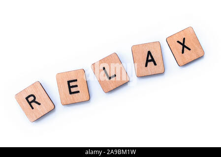 The word RELAX, spelt with wooden letter tiles over a white background. Stock Photo