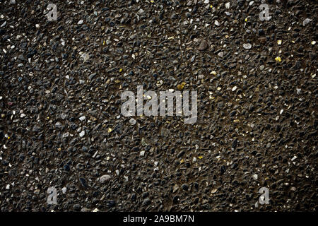 Black asphalt view with inclusion of small golden and white stones - background Stock Photo