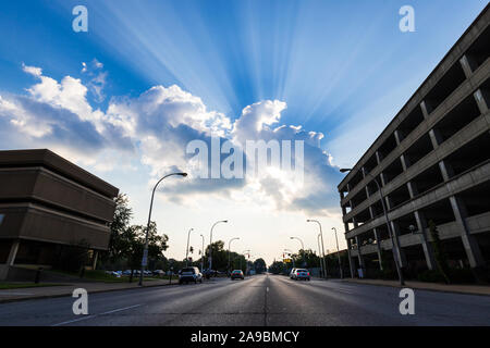 Sun beams shining through clouds on a beautiful summer day in a city. Stock Photo