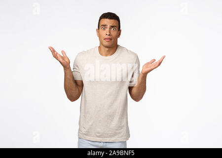 Concerned and alarmed tanned muscline young man standing shocked and confused, shrugging with hands spread sideways, stare camera anxious and Stock Photo