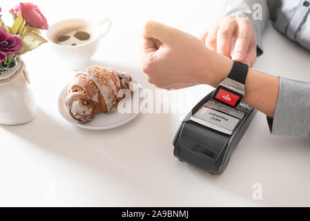 Man using smart watch to pay in restaurant. NFC contactless convenient payment service Stock Photo