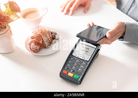 Man using smart phone to pay in restaurant. NFC contactless convenient payment service Stock Photo