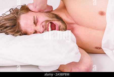 Tips on how to wake up feeling fresh and energetic. Morning routine tips to feel good all day. How to get up in morning feeling fresh. Late morning overslept. Man handsome guy lay in bed in morning. Stock Photo
