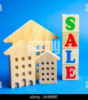 Wooden blocks with the word Sale and wooden miniature houses. The concept of the sell of real estate, apartments and residential premises. Rent and mo Stock Photo