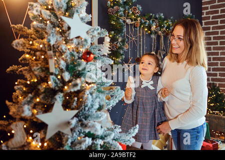 Mother and daughter decorate the Christmas tree. Stock Photo