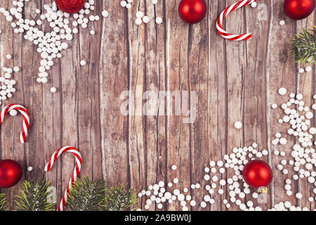 Seasonal Christmas flat lay with traditional red tree ornament baubles, white snow balls, candy canes and fir branches on empty wooden copy space back Stock Photo