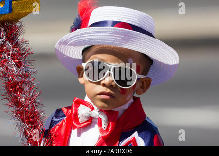 portrait and closeup of the face of a young mixed race child, a boy of circa 5 years old, wearing white sunglasses dressed in fancy dress costume Stock Photo