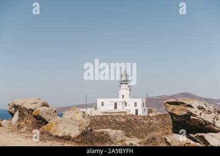 View of Armenistis Lighthouse in Mykonos, Greece, through the rocks, selective focus. Stock Photo