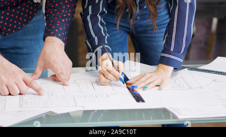 Male and female architect looking over blueprints in modern office Stock Photo