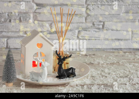 Candles and Christmas decoration on white wooden table with bokeh lights over brick wall. Sweet hime, Christmas time. Stock Photo