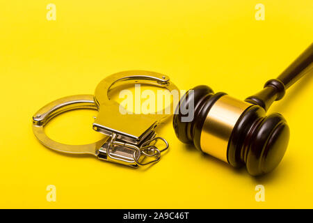 Crime or justice concept showing a gavel on a yellow background with handcuffs Stock Photo