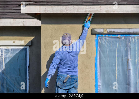 Renovation at home. construction worker putting decorative plaster on house exterior Stock Photo