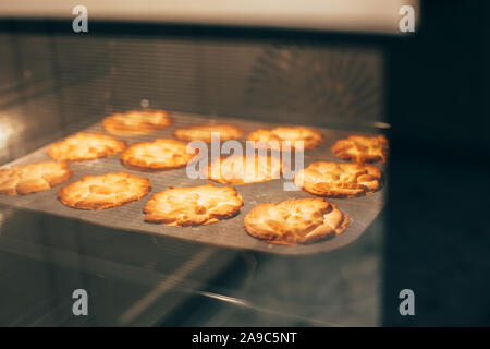 Homemade thanksgiving fall pumpkin pies baking in hot oven for autumn holiday dining. Cozy home mood Stock Photo