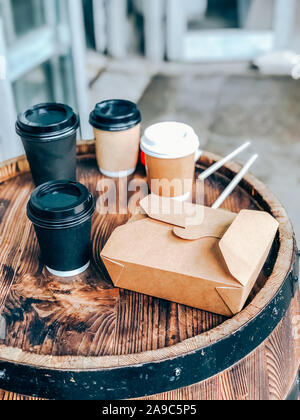 Coffee cups and street food craft paper container on a wooden outdoor table. Street market food and drinks take away waste problem concept. Mobile pho Stock Photo