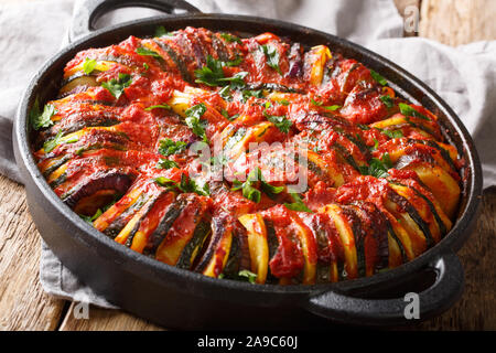 Baked zucchini, potatoes, eggplant and onions in tomato sauce close-up in a pan on the table. horizontal Stock Photo