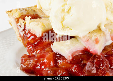 Piece of homemade cherry pie topped off with several scoops of vanilla ice cream on top making it a la mode style. Stock Photo