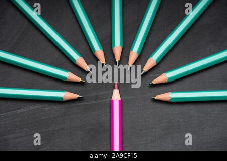 Pink Colored Pencil Surrounded With Green Lead Pencils On Black Chalkboard Stock Photo