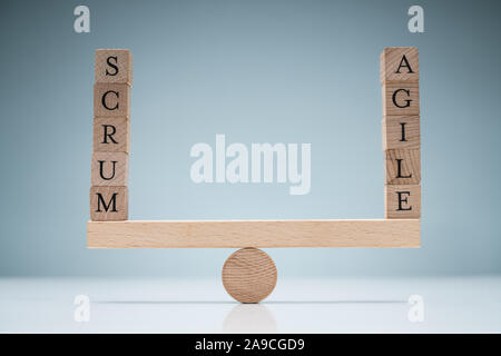 Stack Of Wooden Scrum And Agile Blocks On Seesaw Over The White Desk Stock Photo