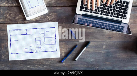 Floor plan drawing with architect designing home on computer, old wooden desk with blueprint of house or apartment project Stock Photo