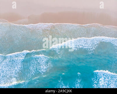 Ocean beach aerial top down view with blue water, waves with foam and spray and fine sand, beautiful summer vacation holidays destination Stock Photo