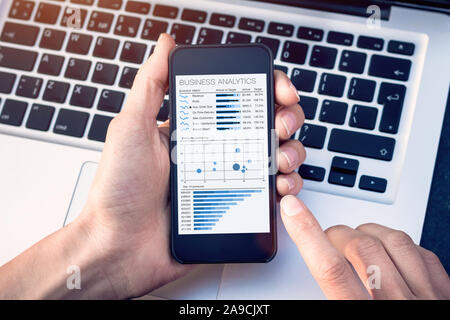 Business analytics dashboard on smartphone screen, analyst analyzing sales and operations data key performance indicators (KPI) charts and metrics Stock Photo