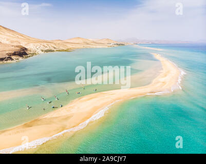Aerial view of beach in Fuerteventura island with windsurfers learning windsurfing in blue turquoise water during summer vacation holidays, Canary isl Stock Photo