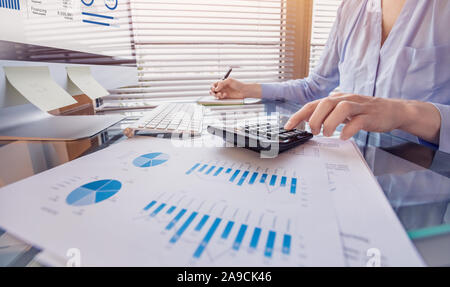 Business person working on financial report and analyzing revenue and expenses data with calculator in office Stock Photo