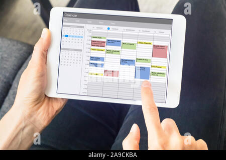 Calendar app on tablet computer with planning of the week with appointments, events, tasks, and meeting. Hands holding device, time management concept Stock Photo