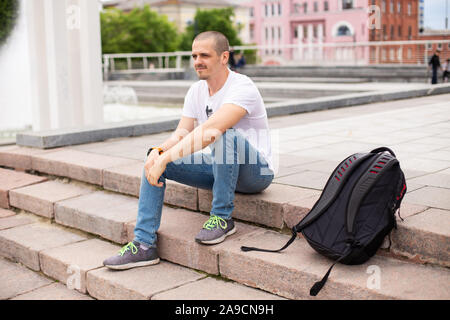 Man traveller sitting on stairs and relaxing in urban park Stock Photo