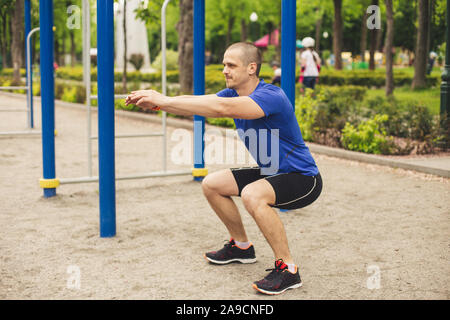 Man doing squats in the sports ground in park Stock Photo