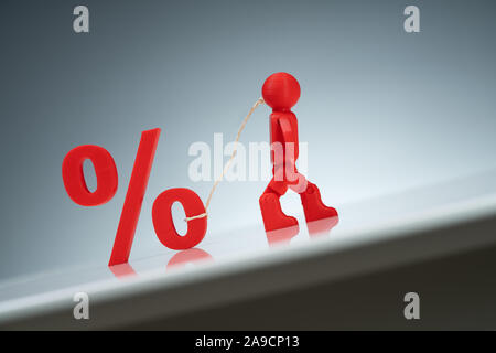 Red Human Figure Pulling Up A Percentage Symbol On A Grey Background Stock Photo