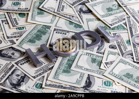 The words HODL laid with aluminium letters and bitcoin shiner on the US dollar banknotes background - with selective focus and diagonal composition. Stock Photo