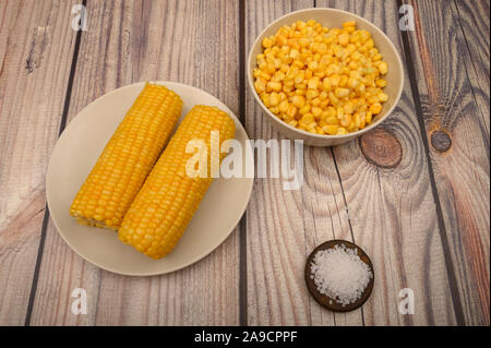 Two ears of boiled corn in a plate and coarse salt on the table. Healthy diet. Fitness diet. For a sweet treat Stock Photo