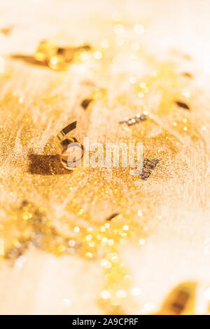 New Year's Eve background with confetti and gold snakes on wooden table, lights Stock Photo