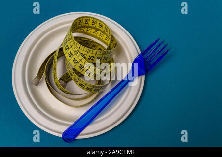 plastic blue fork, plastic plate, measuring tape blue background. closeup Stock Photo