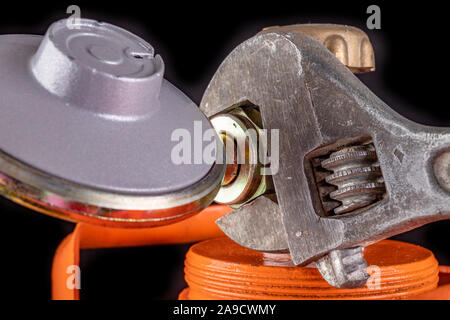 Gas cylinder and propane-butane gas reducer. Installation of a special hose for a metal cylinder. Dark background. Stock Photo