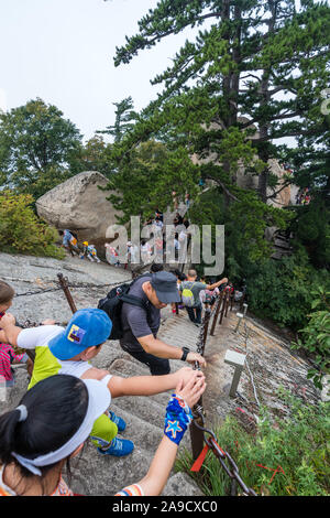 Huashan, China -  August 2019 : Tourists climbing up and descending the stairs on a steep mountain trail to the North and West Peak on Huashan mountai Stock Photo