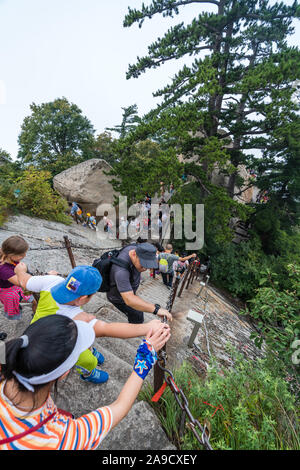 Huashan, China -  August 2019 : Tourists climbing up and descending the stairs on a steep mountain trail to the North and West Peak on Huashan mountai Stock Photo