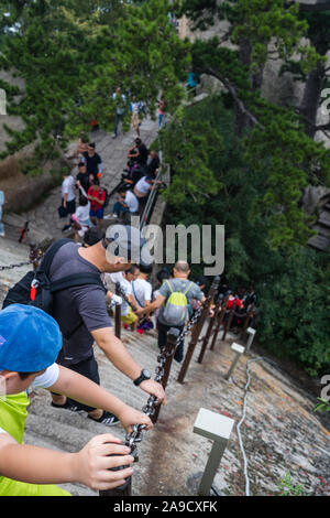 Huashan, China -  August 2019 : Tourists climbing up and descending the stairs on a steep mountain trail to the North and West Peak on Huashan mountai Stock Photo