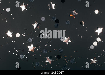 Black festive background with silver sparkles and stars. Flat lay style Stock Photo