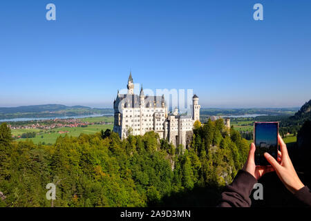 Tourist on Marien bridge takes a photo  of Castle Neuschwanstein with mobile phone, Schwangau, Königswinkel, East Allgäu, Allgäu, Swabian, Bavaria, Ge Stock Photo