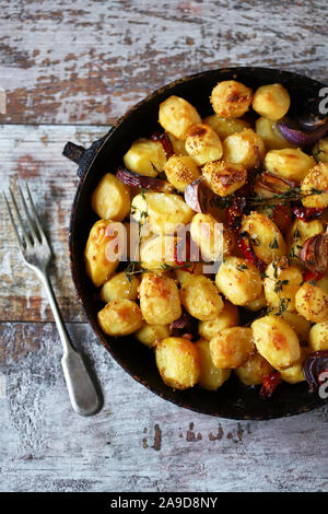 Appetizing baked potatoes whole in a pan. Rustic baked potato with garlic, herbs and spices. Stock Photo