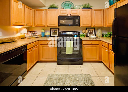 The kitchen features granite countertops, electric appliances, and wood cabinets at Cypress Cove Apartment Homes in Mobile, Alabama. Stock Photo