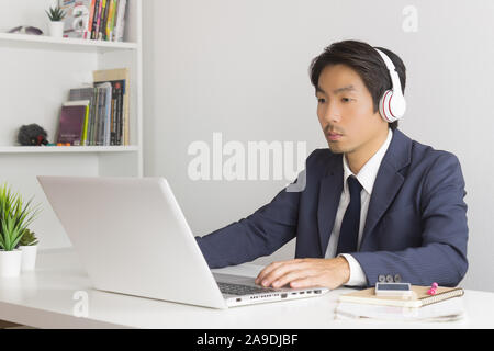 Asian Man Call Center in Suit Wear Headset or Headphone Contacting and Service the Customer Via Internet in Office. Asian man call center working with Stock Photo