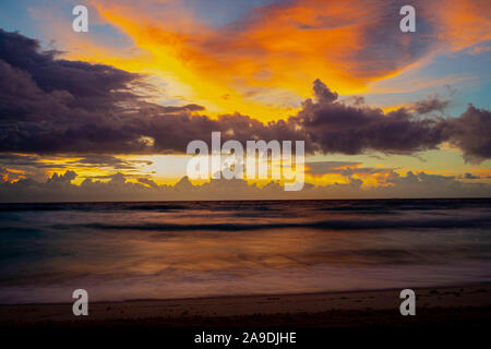 Dramatic sky lights on a cloudy day during sunrise over Caribbean sea. Taken in Cancun, Mexico. Stock Photo