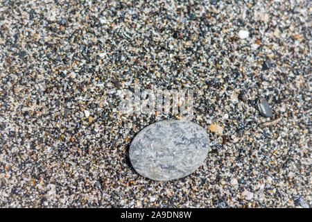 A flat stone lying on a fine pebble beach by the sea Stock Photo