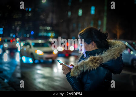 Woman walking and texting in city street at night Stock Photo
